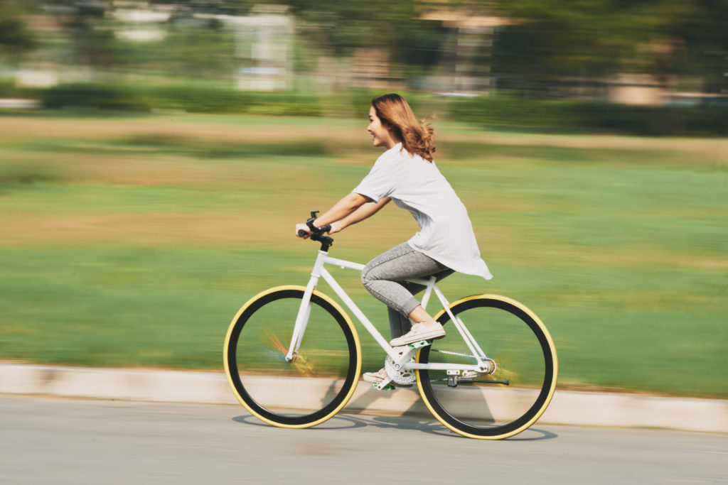 Happy excited young woman riding bicycle at high speed